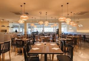 a restaurant with wooden tables and chairs and chandeliers at Delfinia Resort - All Inclusive in Kolimbia