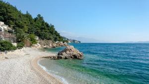 a beach with rocks in the water and trees at Apartmani Jelena in Omiš