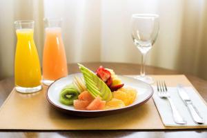 a plate of fruit on a table with a glass of orange juice at NH Santiago del Estero in Santiago del Estero