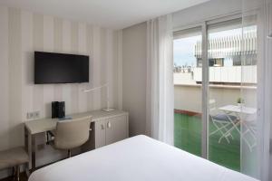 um quarto de hotel com uma cama, uma secretária e uma janela em NH Madrid Balboa em Madri