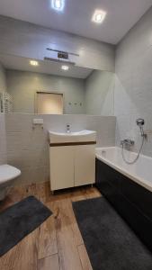 a bathroom with a sink and a tub and a toilet at Apartament Czerwone Maki in Krakow