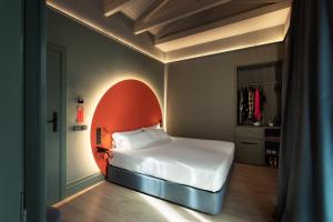a bedroom with a white bed with an orange headboard at chic&basic dot in Madrid