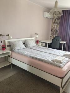 a bedroom with a large bed with a table and a chair at Panorama Apartment Darvenitsa in Sofia