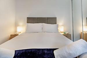 Un dormitorio con una gran cama blanca con dos lámparas. en 2 Challacombe - Luxury Apartment at Byron Woolacombe, only 4 minute walk to Woolacombe Beach!, en Woolacombe