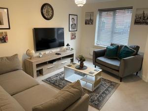 a living room with a couch and a tv at Fresh & Spacious New Build Home in Church Coppenhall