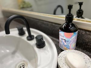 a bottle of soap sitting next to a bathroom sink at Nolan garden house in whitfield in Stratford