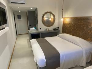 een slaapkamer met een groot bed en een spiegel bij Helios Beach Hotel & Bungalows in Karpathos