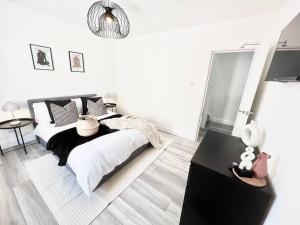 een witte slaapkamer met een bed en een tafel bij Stylish & Spacious 4 Bed Coastal Haven in Weymouth in Weymouth