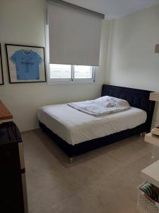 Un dormitorio con una cama y una ventana con una camiseta. en Dudger home en Yehud