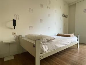 a white bed in a room with a wall at Albergue Guiana in Ponferrada