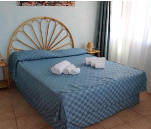 Un dormitorio con una cama azul con toallas. en Residence Il Borgo di Porto Corallo en Villaputzu