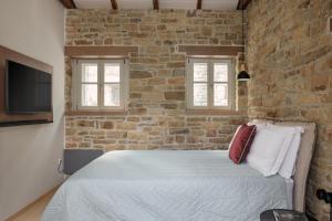 een slaapkamer met een bed en een bakstenen muur bij LozArt Traditional Stone House in Ellinikón