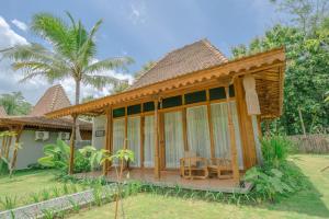 a guest house with a porch and palm trees at Chandaka Borobudur in Magelang