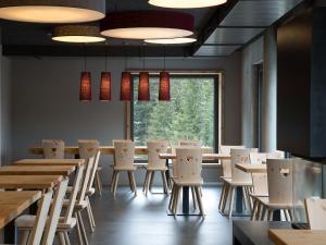 a restaurant with tables and chairs and a large window at Berghotel Mettmen in Schwanden