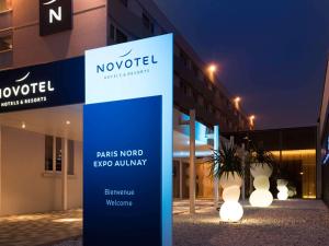 a sign in front of a building with lights at Novotel Paris Nord Expo Aulnay in Aulnay-sous-Bois