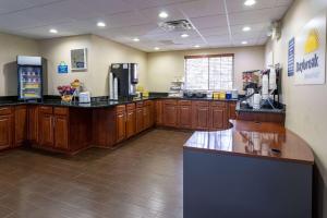 a large kitchen with wooden cabinets and a refrigerator at Days Inn & Suites by Wyndham Cherry Hill - Philadelphia in Cherry Hill