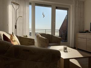 uma sala de estar com um sofá, cadeiras e uma mesa em Haus am Deich Wohnung 13 em Dahme