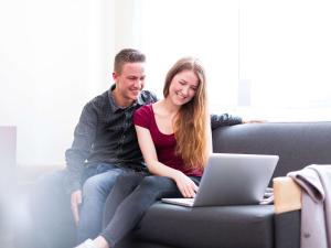 a man and woman sitting on a couch with a laptop at Novotel Suites Hannover in Hannover