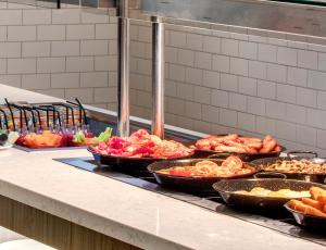 a buffet line with many different types of food in pans at Leonardo Hotel Middlesbrough in Middlesbrough