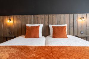 two beds with orange pillows in a bedroom at Hotel Rooms in Breskens