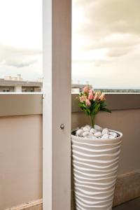Giramondo LuxeFierairport في فيوميتشينو: مزهرية بيضاء مع وردة على شرفة