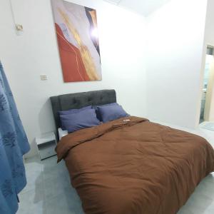 Cama con manta marrón y almohadas azules en KuantanBukitSetongkolArea3R2B.HTAA/TOWN-5min only en Kuantan