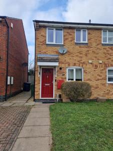 a red brick house with a red door at Cheerful Two-Bedroom Residential Home in Oxford