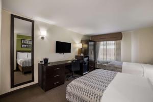 a hotel room with a bed and a desk with a mirror at SureStay Plus by Best Western Mesa Superstition Springs in Mesa