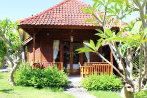 a small wooden house with a porch in a garden at Bamboo Bungalow Jungle View in Nusa Penida