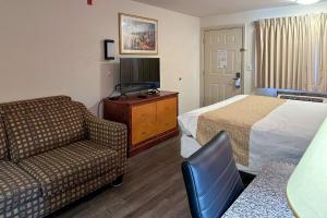 a hotel room with a bed and a couch and a tv at Econo Lodge Edmonds North Seattle in Edmonds