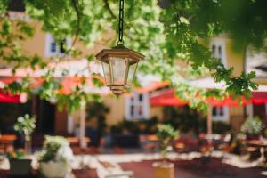 a lamp hanging from a tree with a patio in the background at Gasthof Zum Hirsch in Fürstlich Drehna