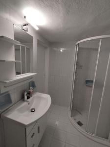 a white bathroom with a sink and a shower at Center of Parga-John's House in Parga