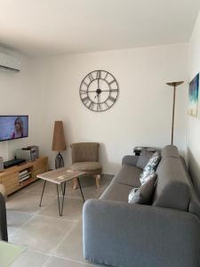 uma sala de estar com um sofá e um relógio na parede em Le Poseidon em Saint-Raphaël