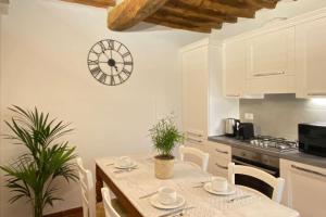 a kitchen with a table and a clock on the wall at Relax&Business [Wi-fi, TV HD, Parcheggio gratuito] in Capannori