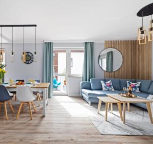 a living room with a blue couch and tables at Mevka Apartamenty Mosty in Mosty