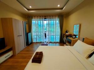 ein Schlafzimmer mit einem großen weißen Bett und einem TV in der Unterkunft Rimwang The River Life in Sai Yok