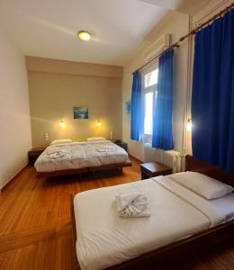 two beds in a room with blue curtains at Vassilikon Hotel in Loutraki