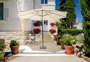 ein Regenschirm vor einem Haus mit Topfpflanzen in der Unterkunft Palace Schön Milesi - esense of prestige - BURALUX properties in Split
