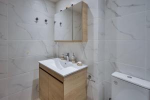 a white bathroom with a sink and a toilet at Downtown Guesthouse by Estia in Heraklio Town