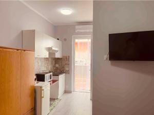 a kitchen with white cabinets and a tv on the wall at M&C Apartment in Fiumicino