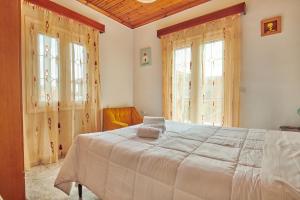 a bedroom with a large bed and two windows at Villa Roxa Montuoso in Agios Leon
