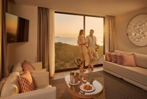 a couple standing in a living room with a large window at TRS Ibiza Hotel - Adults Only in San Antonio