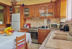 a kitchen with wooden cabinets and a table with a bowl of fruit at Villa Roxa Montuoso in Agios Leon