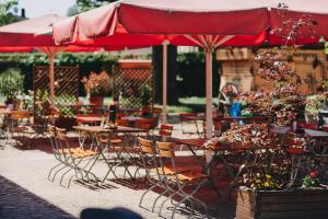 eine Terrasse mit Tischen, Stühlen und einem roten Regenschirm in der Unterkunft Gasthof Zum Hirsch in Drehna