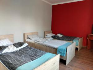 a room with two beds and a red wall at Apartament Ogrodowa in Muszyna