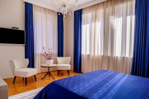 1 Schlafzimmer mit einem blauen Bett, 2 Stühlen und einem Kronleuchter in der Unterkunft Palace Schön Milesi - esense of prestige - BURALUX properties in Split