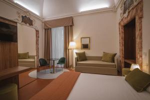 グッビオにあるHotel Villa Montegranelliのベッドとソファ付きのホテルルーム