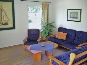 een woonkamer met een blauwe bank en 2 stoelen bij Ferienhaus Schüler mit Terrasse und Garten in Zinnowitz