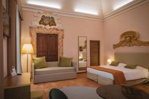 グッビオにあるHotel Villa Montegranelliのベッドルーム1室(ベッド2台、ソファ、鏡付)