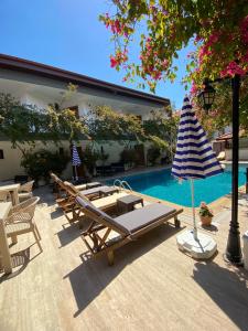 uma piscina com espreguiçadeiras e um guarda-sol em EON DALYAN BOUTIQIE HOTEL em Ortaca